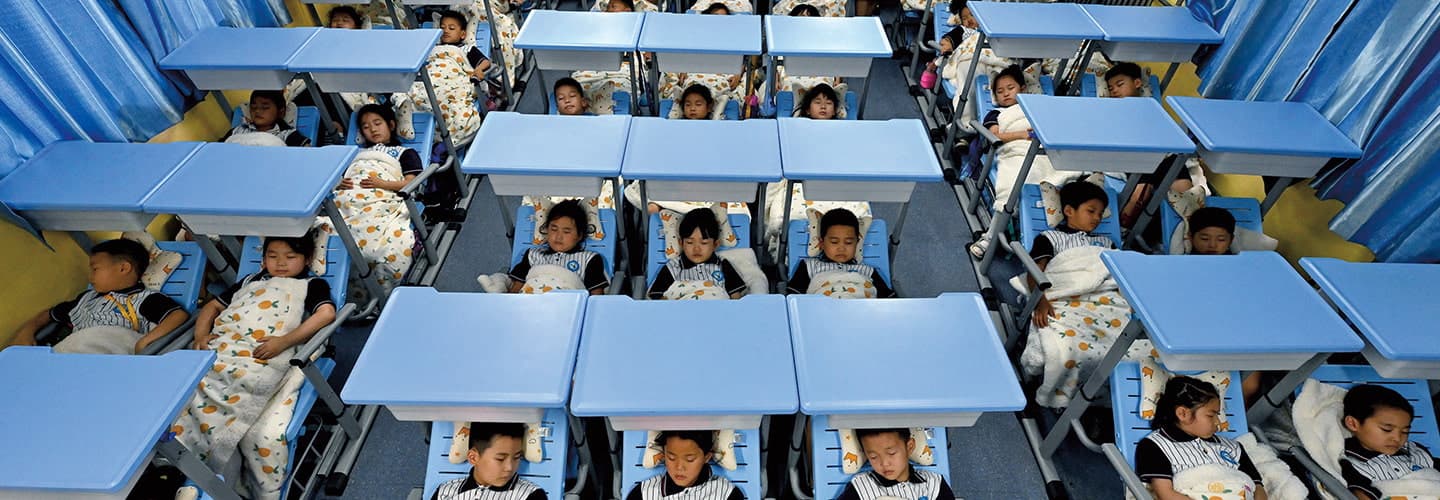 Photo of rows of students taking naps in beds during school