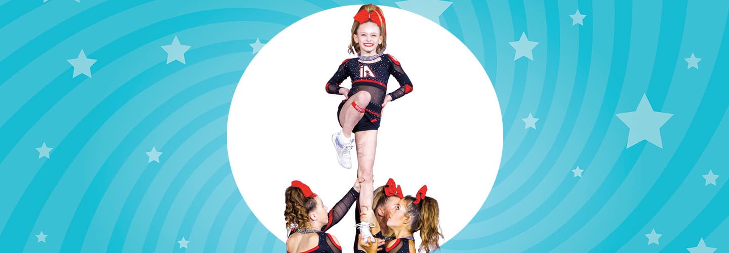 Image of a cheerleader being held up by teammates